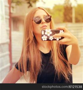 Young woman taking a selfie outdoors on sunny summer day. Photo toned style Instagram filters