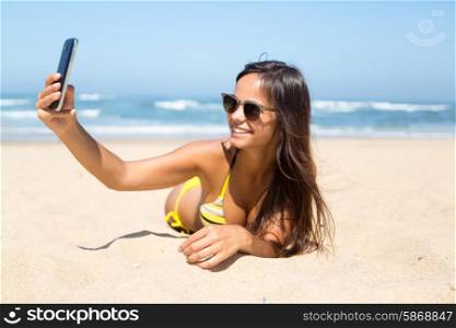Young woman taking a selfie while relaxing at the beach