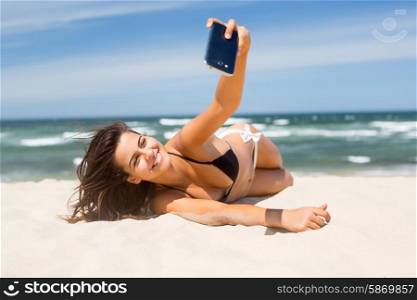 Young woman taking a selfie while relaxing at the beach