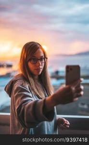 Young woman taking a selfie with the ocean on the background