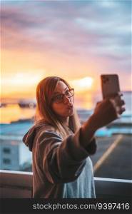 Young woman taking a selfie with the ocean on the background, making gestures