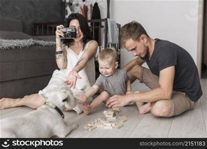 young woman taking dog with camera sitting near his son husband playing together