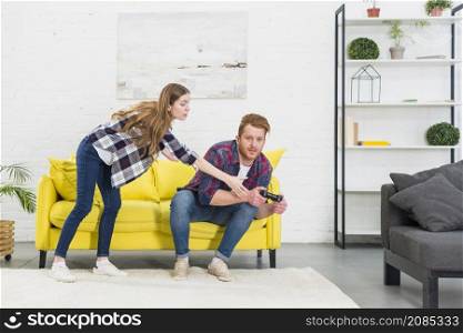 young woman taking joystick from his boyfriend playing video game