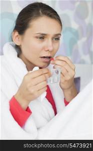 Young woman taking medicine in bedroom at home