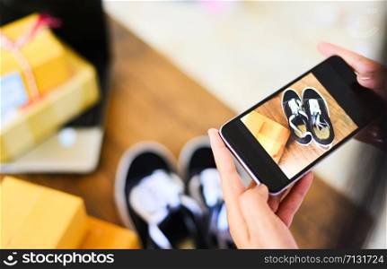 young woman taking photo sneakers with camera smartphone for post to sell online on the internet market website / selling online ecommerce shipping online shopping delivery and order concept