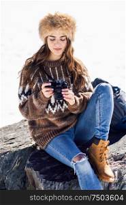 Young woman taking photographs in the snowy mountains in winter, in Sierra Nevada, Granada, Spain. Female wearing winter clothes.. Young woman taking photographs in the snowy mountains