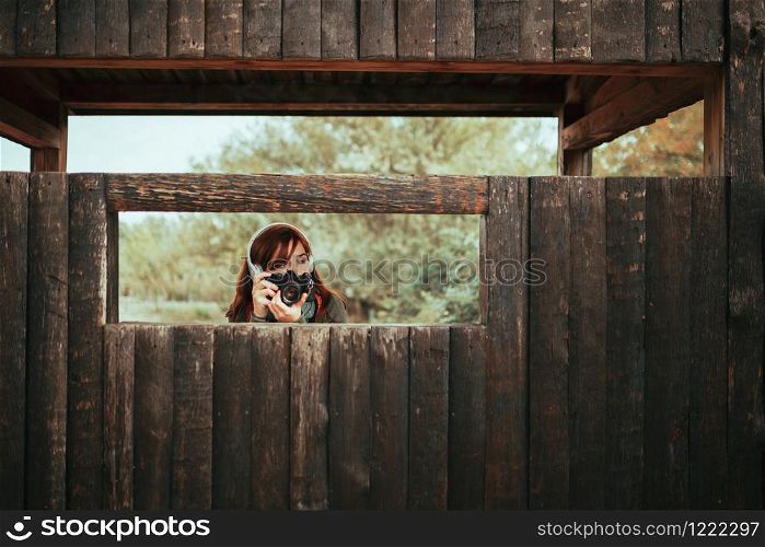 Young woman taking photos from wooden hut in the forest