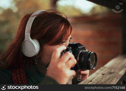 Young woman taking photos from wooden hut in the forest