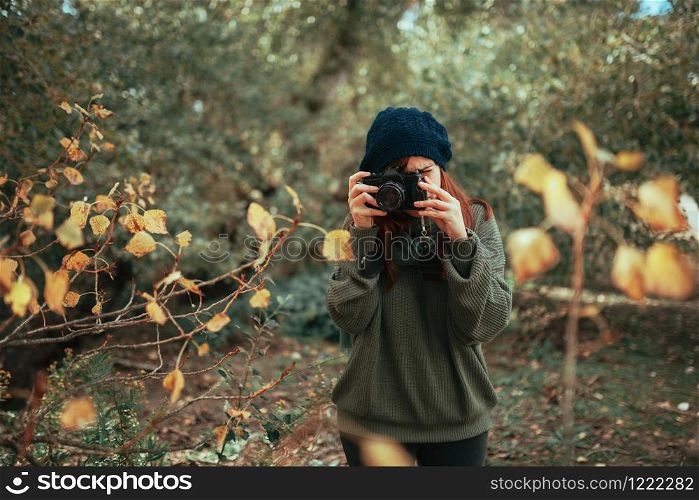 Young woman taking photos in the forest with an old analog camera