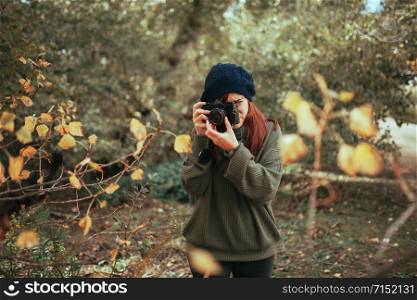 Young woman taking photos in the forest with an old analog camera