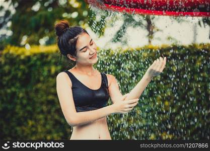 Young woman taking shower at swimming pool in luxury resort hotel. Travel and summer lifestyle.. Woman taking shower at swimming pool in resort.