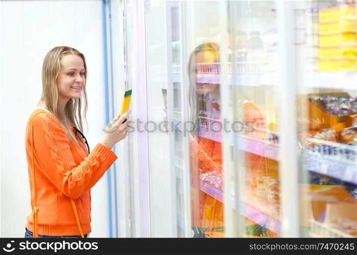 Young woman taking tube from the showcase in the grocery
