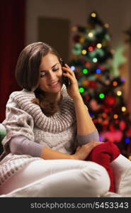 Young woman talking cell phone near christmas tree