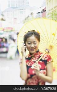 Young woman talking on a mobile phone holding a parasol
