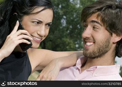 Young woman talking on a mobile phone with a young man smiling