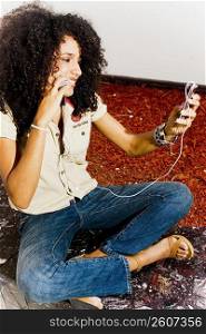 Young woman talking on cell phone while listening to music