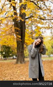 Young woman talking on mobile phone and smiling in autumn park