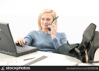 Young Woman Talking on Phone and Working on Laptop