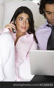 Young woman talking on the telephone with a mid adult man using a laptop