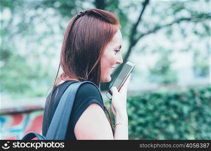 Young woman talking to smartphone in park