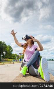 Young woman testing VR eyeglasses outside. Female wearing virtual reality headset during summer weather with dark clouds.. Woman wearing VR outside