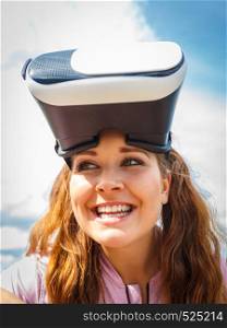 Young woman testing VR eyeglasses outside. Female wearing virtual reality headset during summer weather.. Woman wearing VR outside