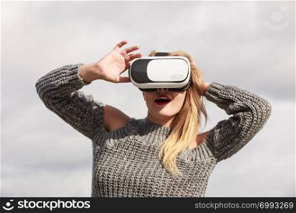 Young woman testing VR glasses outside. Female wearing virtual reality headset during spring weather,. Woman wearing VR outside