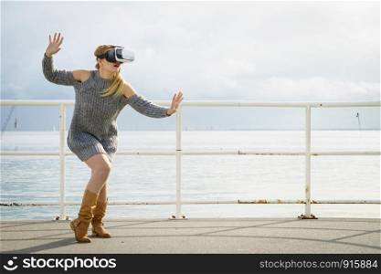 Young woman testing VR glasses outside. Female wearing virtual reality headset during spring weather,. Woman wearing VR outside