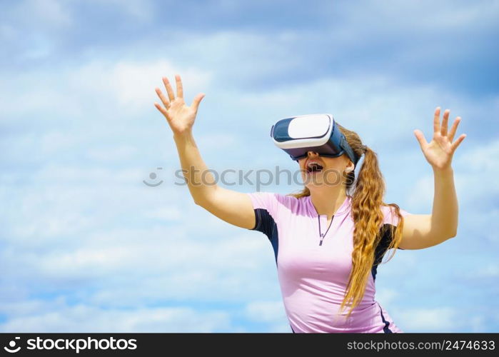 Young woman testing VR glasses outside. Female wearing virtual reality headset during summer weather. Woman wearing VR outside