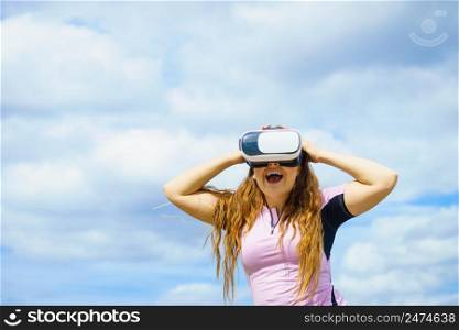Young woman testing VR glasses outside. Female wearing virtual reality headset during summer weather. Woman wearing VR outside