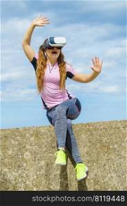 Young woman testing VR glasses outside. Female wearing virtual reality headset during summer weather,. Woman wearing VR outside