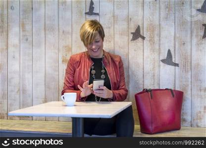 Young woman texting on the phone in a cafe.
