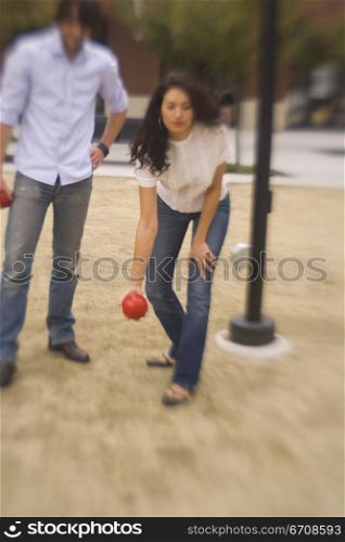Young woman throwing a ball with a young man standing beside her