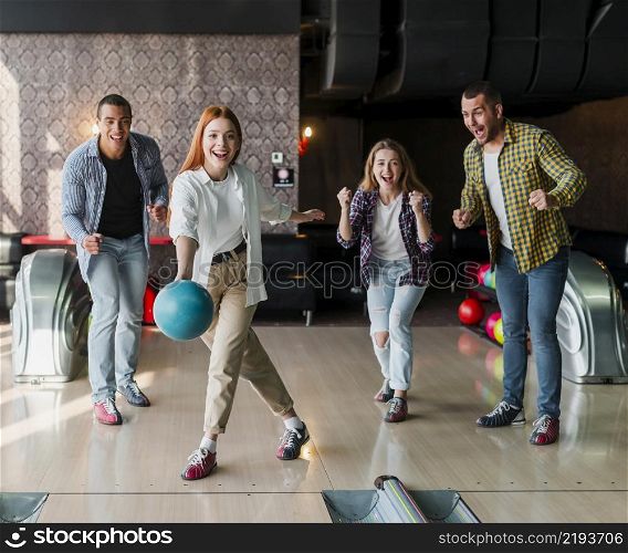 young woman throwing bowling ball alley