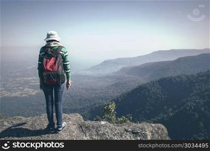 Young woman tourist with backpack standing valley view from top of a mountain. Young woman tourist with backpack standing valley view from top