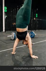 Young woman training on floor in a gym doing handstand walk