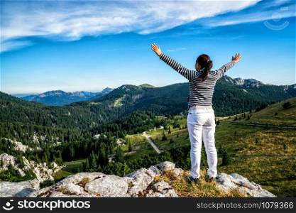 Young woman traveler and explorer travels in the forest and mountain nature landscape hiking across Zavizan Gora in Croatia.
