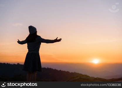 Young woman traveler looking at sunrise over the mountain