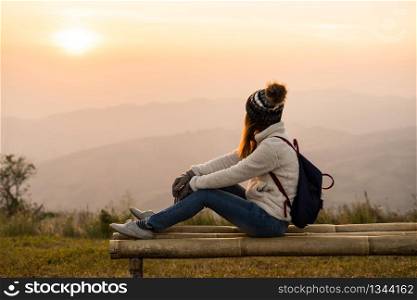 Young woman traveler looking at sunrise over the mountain. Young woman traveler looking at sunrise
