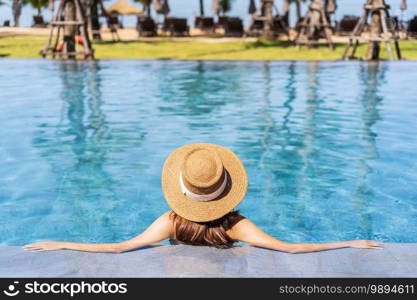 Young woman traveler relaxing and enjoying by a tropical resort pool while traveling for summer vacation, Travel concept