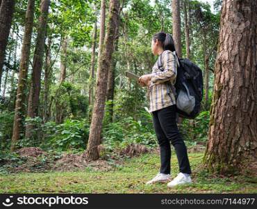 Young woman traveler searches GPS coordinates on tablet in forest on summer vacations day. Lifestyle hiking concept.