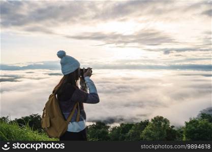 Young woman traveler taking a beautiful sunrise and the sea of mist on the mountain in the morning, Travel lifestyle concept