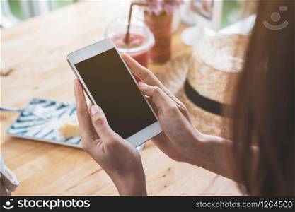 Young woman traveler using smart phone with drinks in cafe while traveling