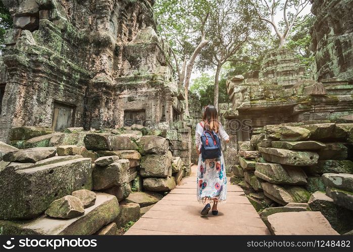 Young woman traveler visiting in ta prohm temple at Angkor Wat complex, Khmer architecture heritage in Siem Reap, Cambodia