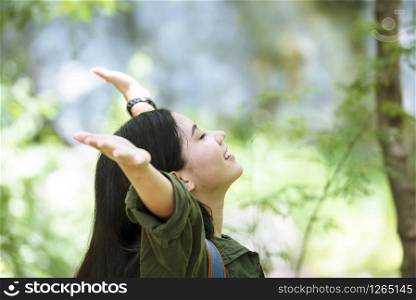Young woman traveler with a green nature relaxation in the park. Asian woman smiling and look at the camera. Travel Concept