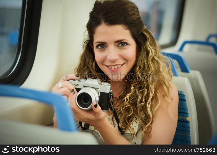 Young woman traveler with vintage camera traveling by the train sitting near the window. Enjoying travel concept.