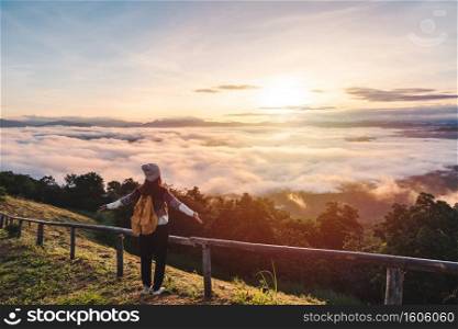 Young woman travelers looking at the sunrise and the sea of mist on the mountain in the morning, Travel lifestyle concept