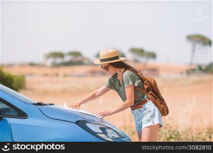 Young woman traveling by car in Tuscany. Girl make a stop to look for right way. Woman for a new adventure looking for the right way on the map