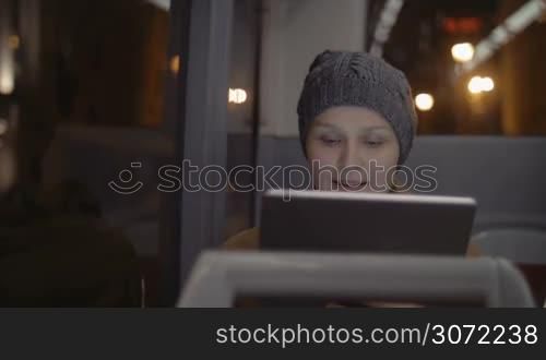 Young woman traveling in the city by bus. She using touch pad during the trip
