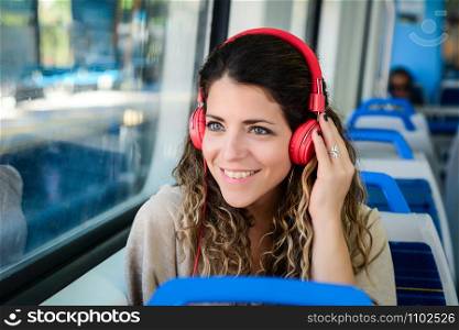 Young woman travelling by train with red headphones.